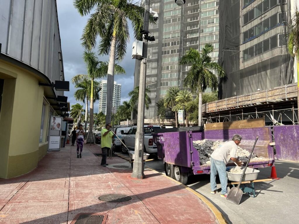 Crew loading debris into a Royal Dumpsters dumpster during a live load in Miami Beach, FL